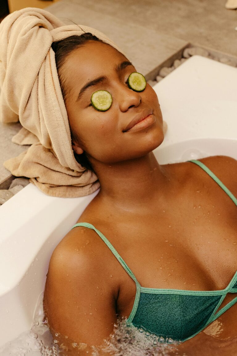 Woman relaxing in a bathtub with cucumber slices on eyes, enjoying a spa treatment.